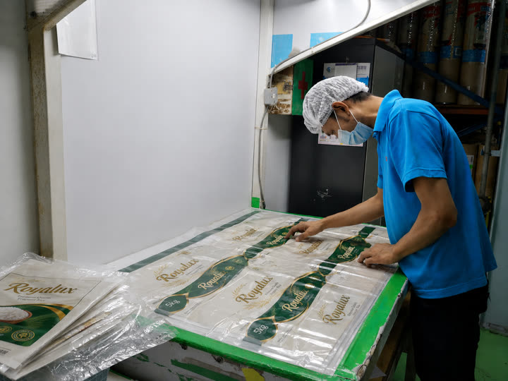 Operator inspecting freshly printed rice-bag film sheets